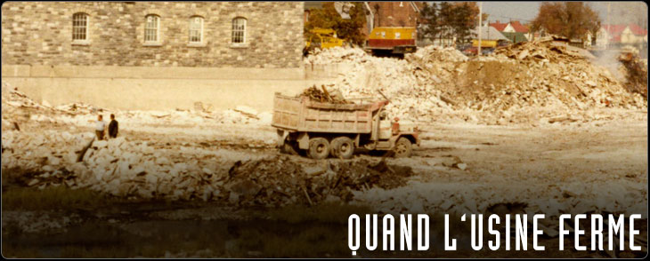 En avant-plan, camion sur un terrain en démolition, en arrière-plan, un bâtiment, une pelle mécanique et une église.